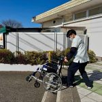 スーパーの階段を活用して、安全確認をしながら車いす階段介助を行う新人スタッフの研修風景