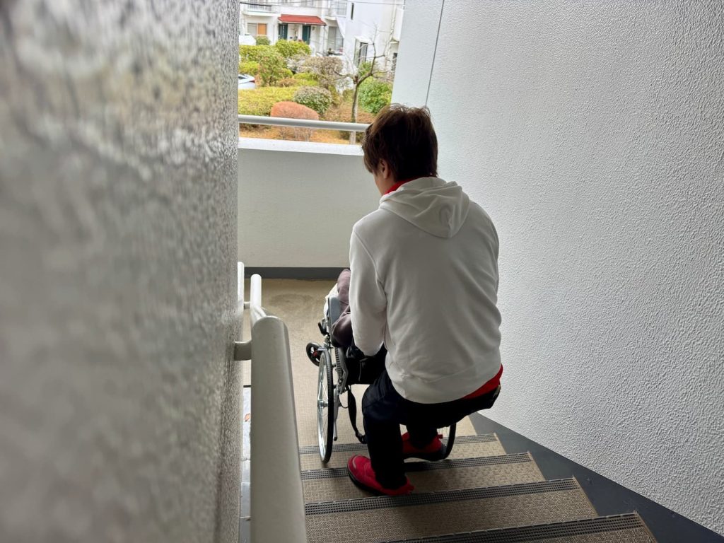 車いすのまま階段介助をするスタッフ