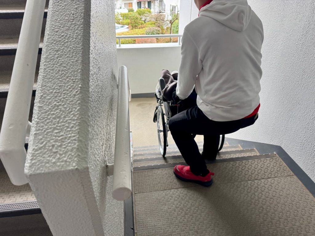 ゆっくりとお声がけしながら車いすのまま階段介助をするスタッフ