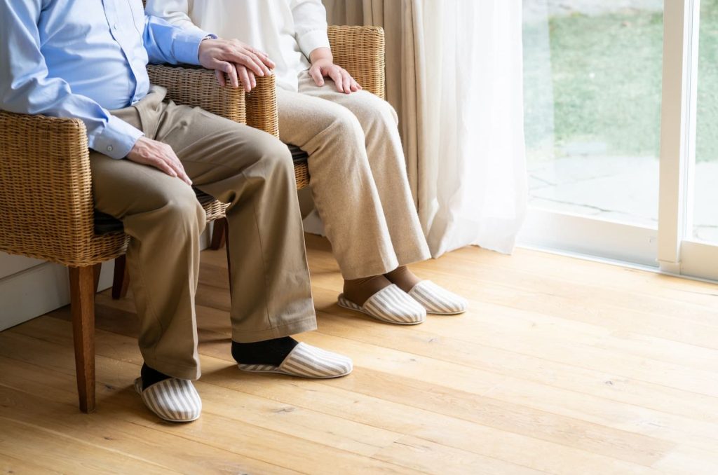 ソファに座り、これからのことを静かに話し合う高齢の夫婦