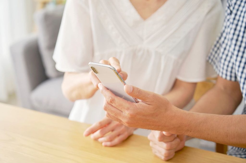 自宅でスマートフォンを見ながら一緒に調べる高齢の夫婦