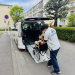 福祉介護タクシーのスロープ車両から車いすに乗ったお客さまを移乗する様子