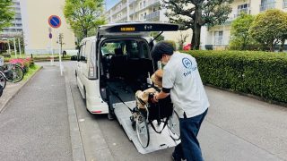 福祉介護タクシーのスロープ車両から車いすに乗ったお客さまを移乗する様子