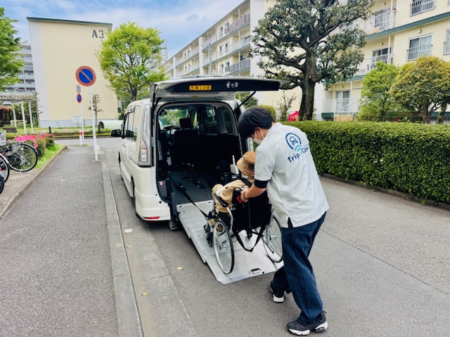 福祉介護タクシーのスロープ車両から車いすに乗ったお客さまを移乗する様子