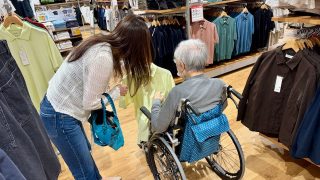 ユニクロで洋服を選ぶ車いすの高齢者と家族