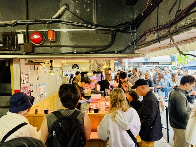 築地場外市場商店街のすし屋カウンターで立ちながら食べる外国人