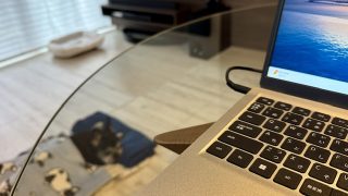 ガラステーブルにノートパソコン、その下にフレンチブルドッグが寝ている様子